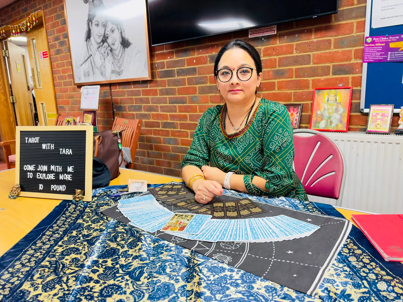 Tara giving a live tarot reading at a community event table marked 'Tarot with Tara'.